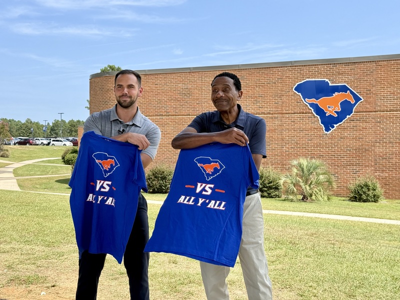 FOX54 Morning Anchor and Chief Meteorologist  holding Midland Valley High t-shirts outside the school.
