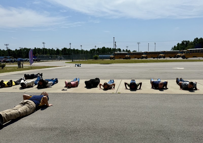 MVHS NJROTC cadets, instructor, and two FOX54 members completing a push up challenge outside the school.