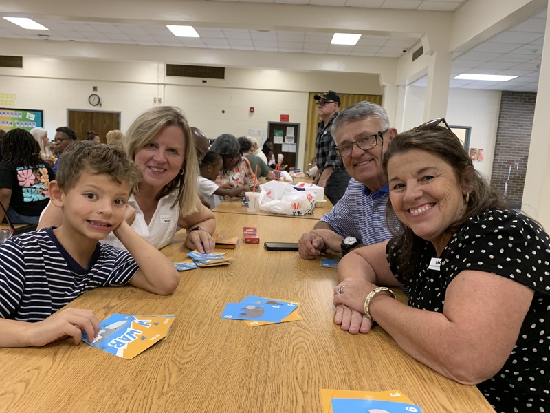 Grandparents Day celebration at elementary school, grandmother with grandchild holding sign. 