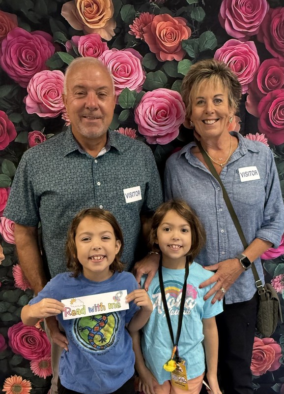 Grandparents Day celebration at elementary school, grandmother with grandchild holding sign. 