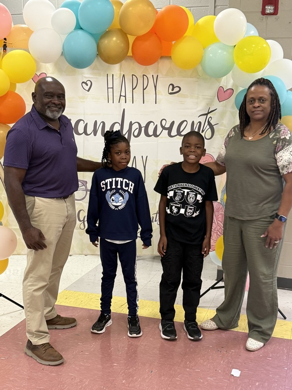 Grandparents Day celebration at elementary school, grandmother with grandchild holding sign. 