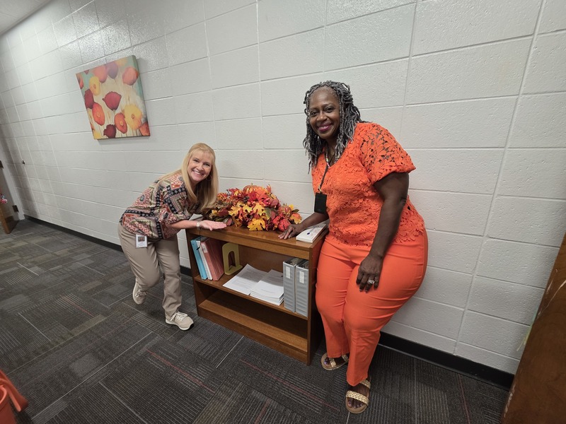 Two women posing with floral arrangement.