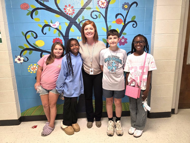 Four students and principal standing in front of blue wall.