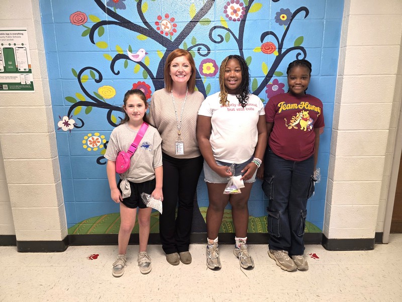 Three  students and principal standing in front of blue wall.