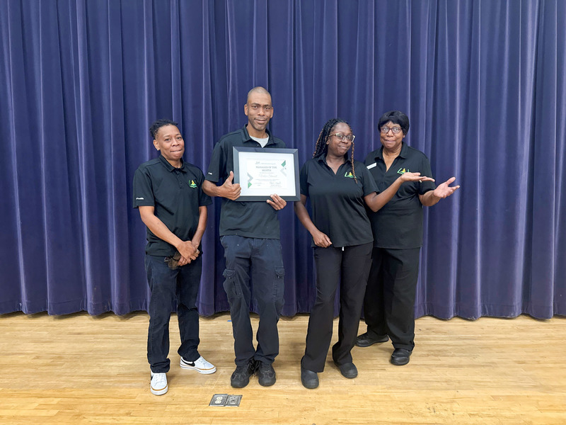 Child Nutrition Manager Victor Stewart holds a certificate and stands with Paul Knox Middle Child Nutrition team members