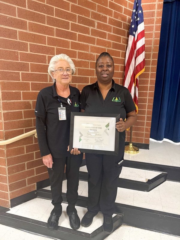 Child Nutrition Professional Georgia Jackson holds a plaque and stands with Mossy Creek Elementary Child Nutrition Manager Marcia Bush