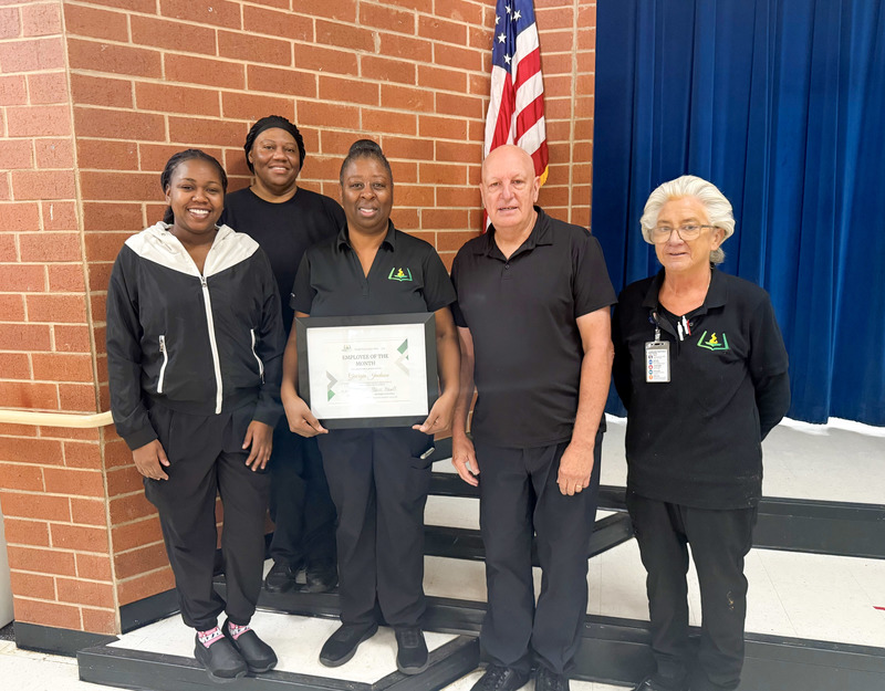 Child Nutrition Professional Georgia Jackson holds a plaque and stands with Mossy Creek Elementary Child Nutrition team members