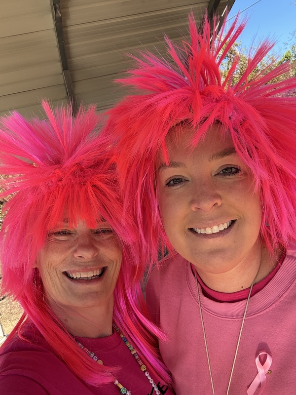 Two teachers with bright pink wigs.