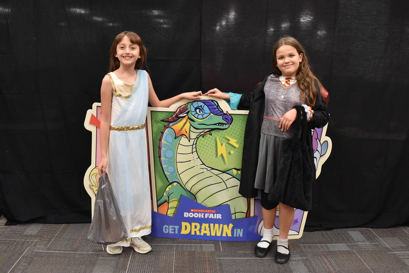 Students by Book Fair sign.