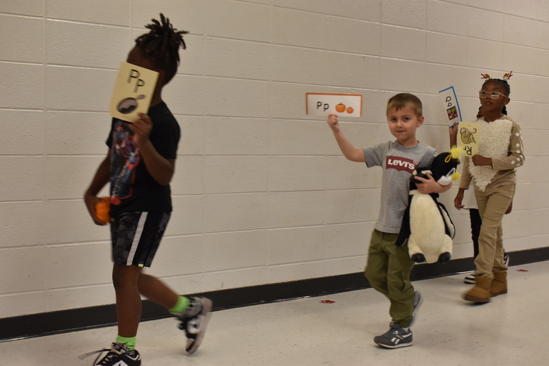 Students wearing costumes to represent letters of the alphabet in a parade.