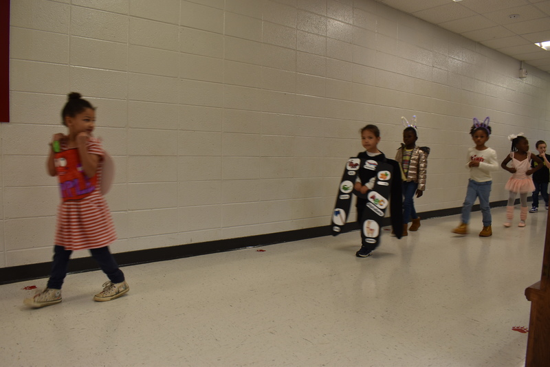 Students wearing costumes to represent letters of the alphabet in a parade.