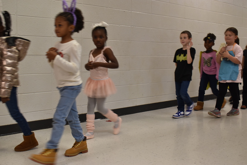 Students wearing costumes to represent letters of the alphabet in a parade.