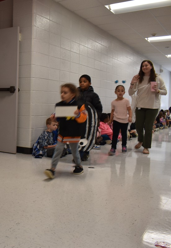 Students wearing costumes to represent letters of the alphabet in a parade.