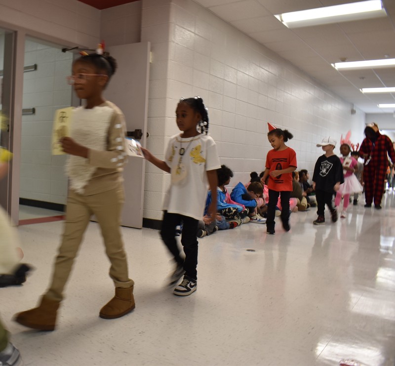 Students wearing costumes to represent letters of the alphabet in a parade.