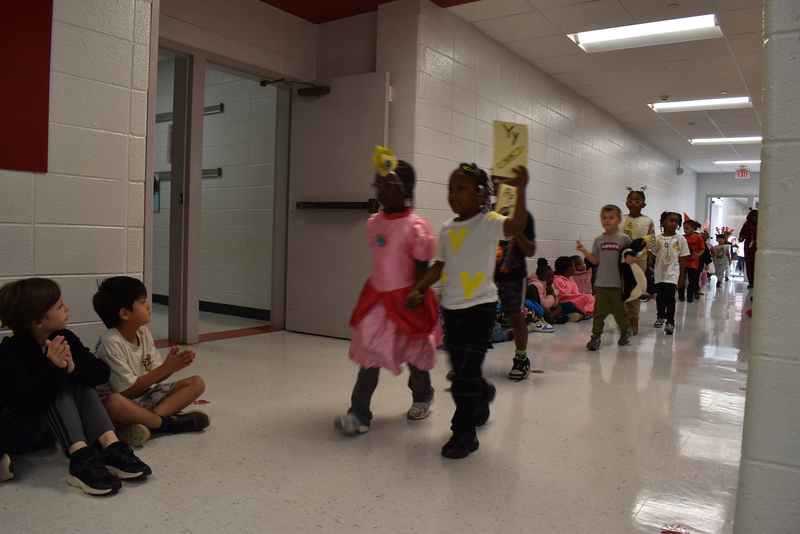 Students wearing costumes to represent letters of the alphabet in a parade.