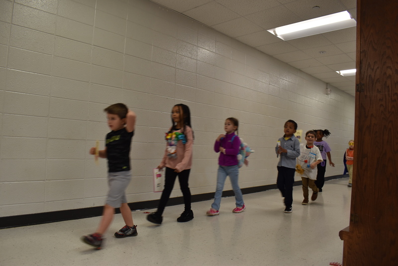 Students wearing costumes to represent letters of the alphabet in a parade.