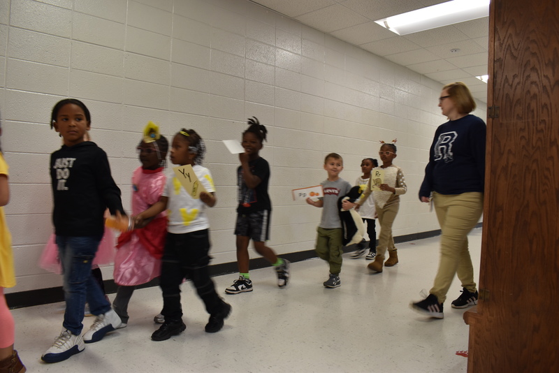 Students wearing costumes to represent letters of the alphabet in a parade.