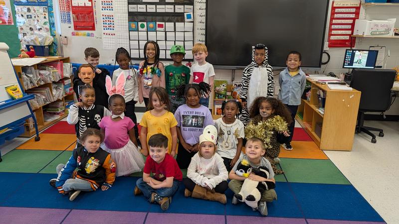 Students wearing costumes to represent letters of the alphabet in a classroom.