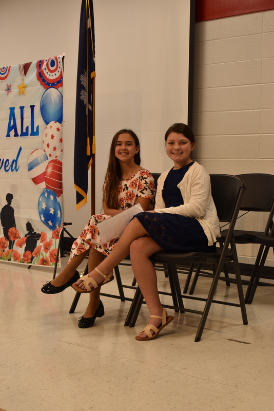 Student presenters sitting on stage.