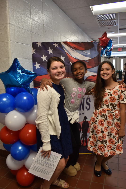 Three students standing by sign.