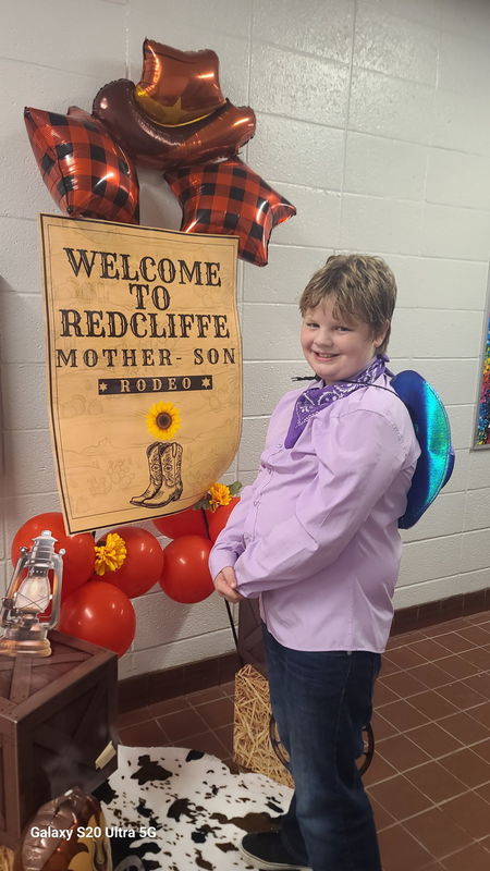Boy in front of Rodeo sign.