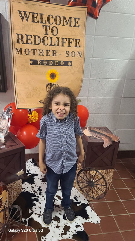 Boy in front of Rodeo sign.