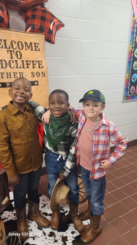 Three boys in front of Rodeo sign.