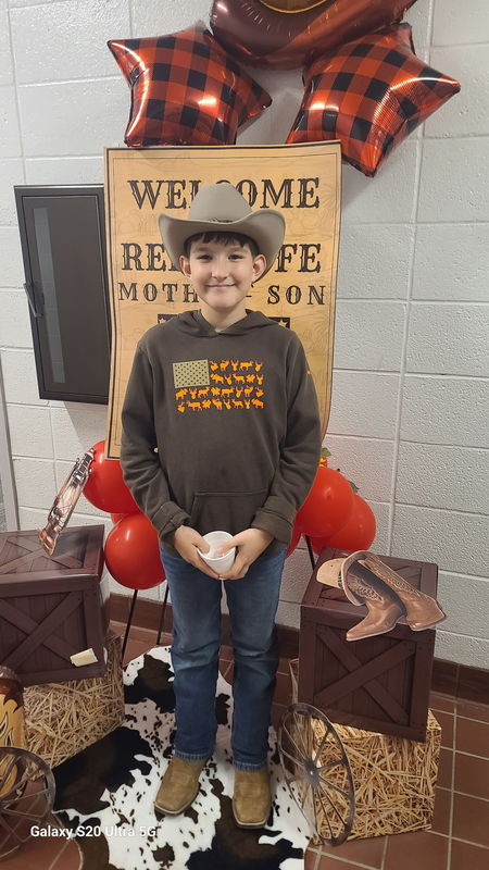 Boy in front of Rodeo sign.