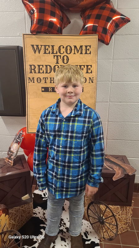 Boy in front of Rodeo sign.