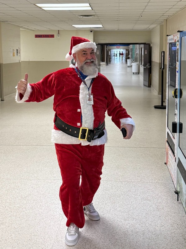 Principal Higgenbottom dressed up as Santa walking down a hallway.