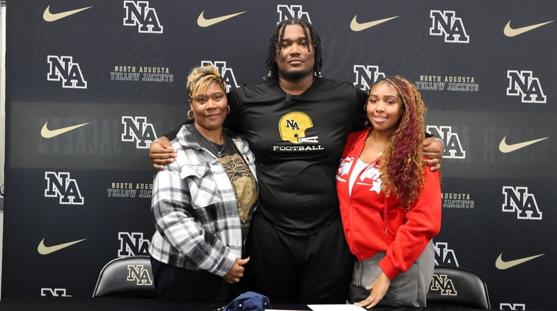 Football Player with arms around two women.