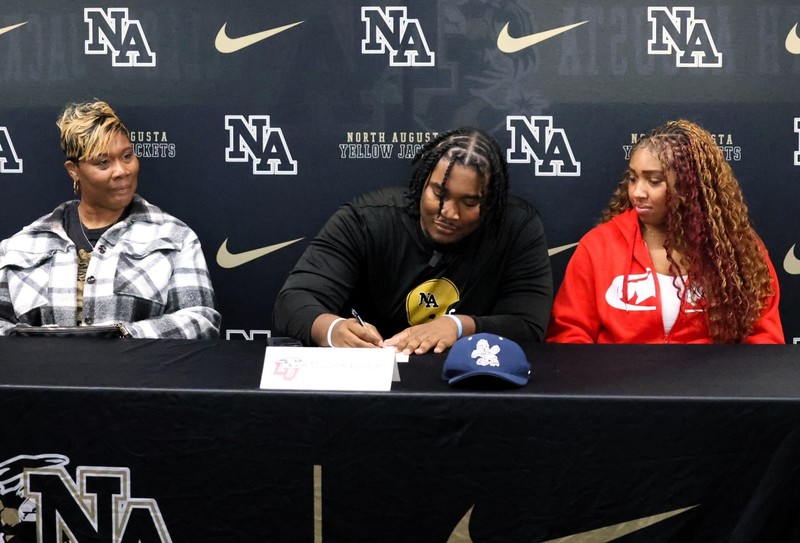 Football Player sitting at table signing in front of NAHS table.