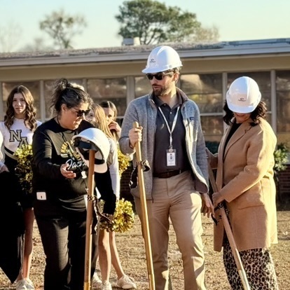 Teachers and staff of NAMS getting ready to "break gound" holding shovels wearing hard hats.
