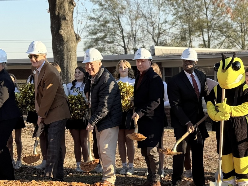 Men wearing hardhats throwing dirt at a groundbreaking ceremony at NAMS.