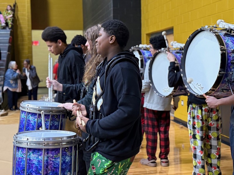 student playing drums at a school assembly.