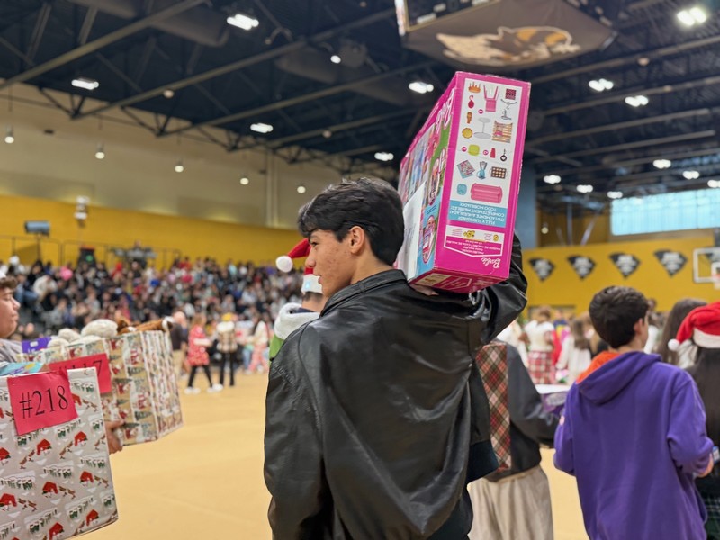 Student walking with a large gift on his shoulders.