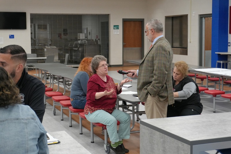 Parent speaking on mic at community input meeting.