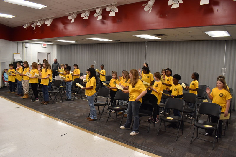 Students standing in front of chairs.