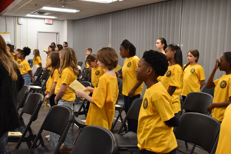 Students standing in front of chairs.
