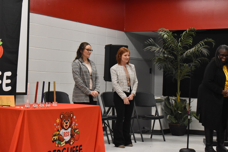 Staff on stage next to table.