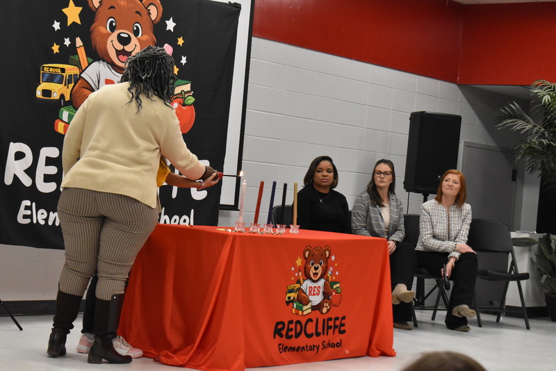 Student and teacher lighting candle.