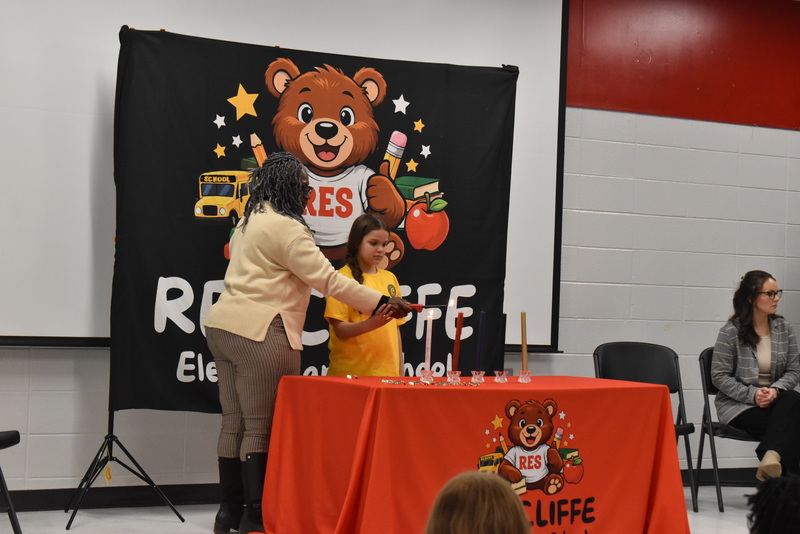 Studen and teacher lighting candle.