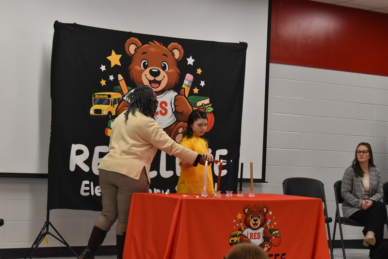 Student and teacher lighting candle.