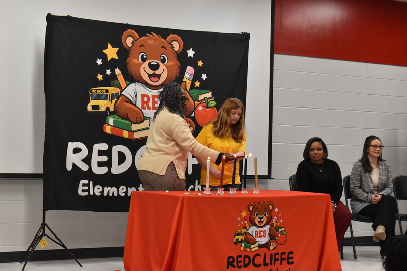 Student and teacher lighting candle.