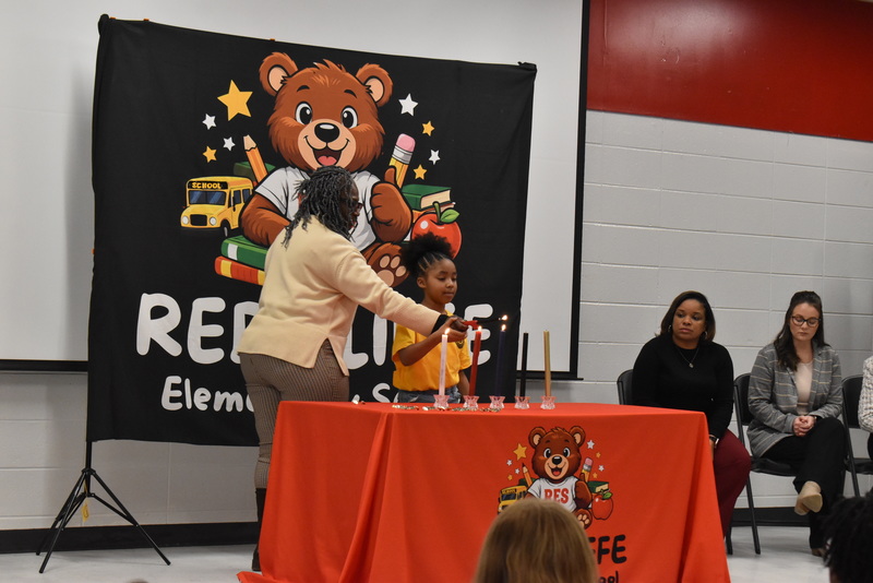 Student and teacher lighting candle.