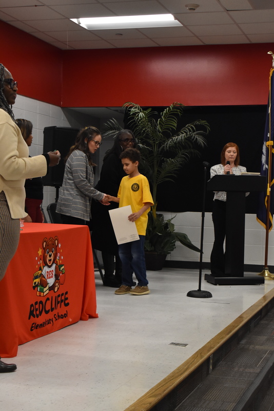 Student on stage shaking hands with staff.