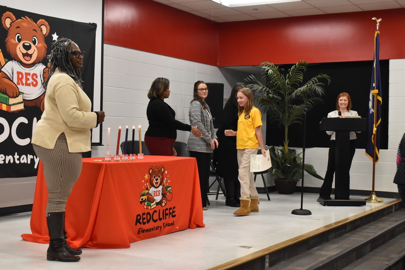Student on stage shaking hands with staff.
