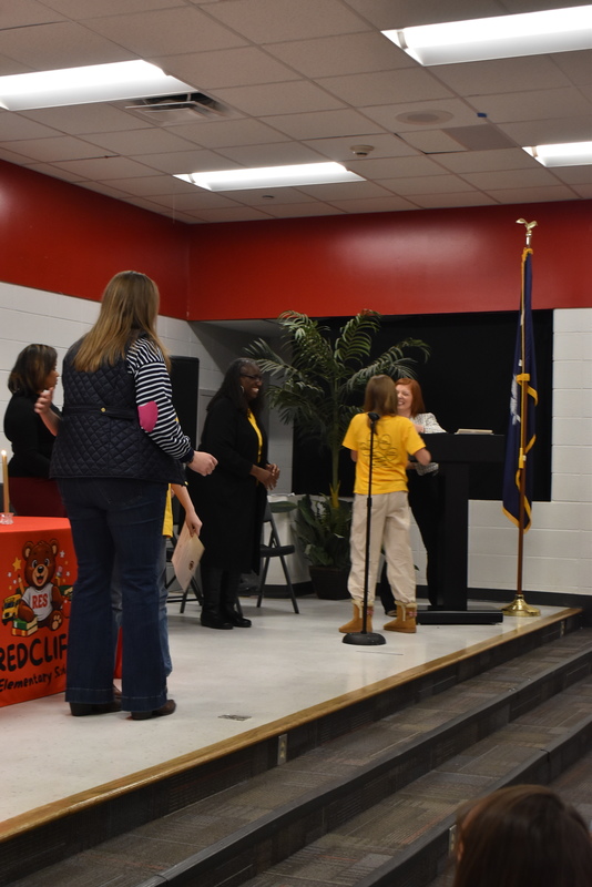 Student on stage shaking hands with staff.