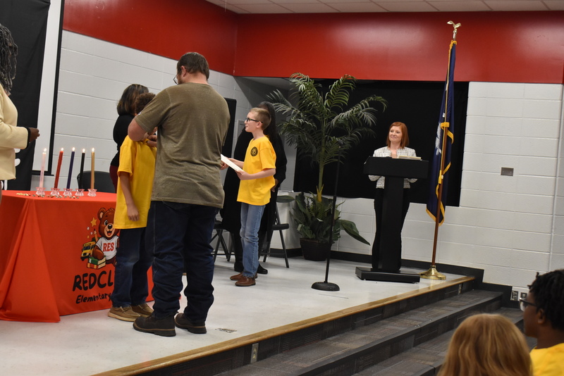 Student on stage shaking hands with staff.