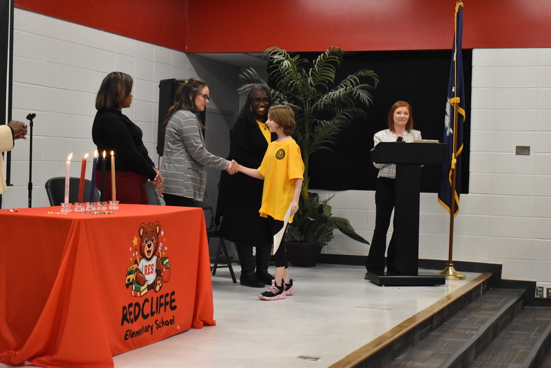 Student on stage shaking hands with staff.